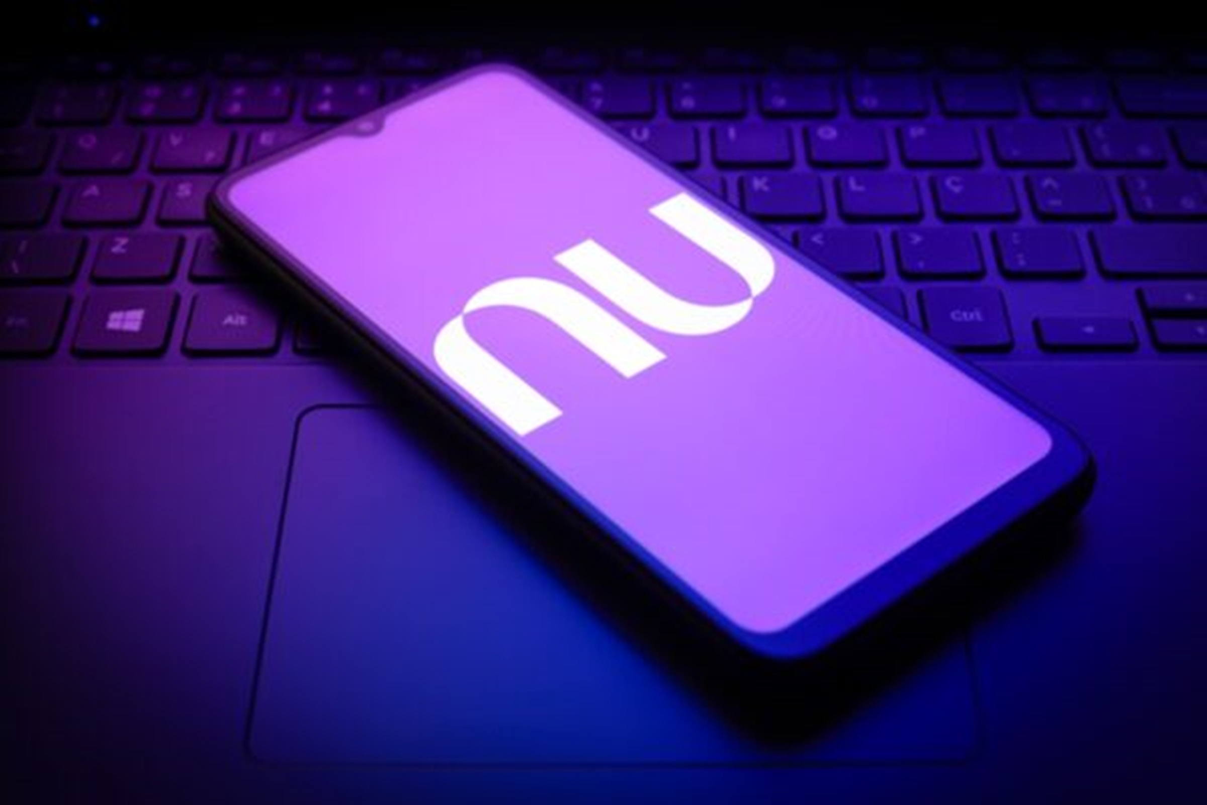 Imagem-de-telefone-celular-em-cima-de-um-teclado-de-notebook-exibindo-a-logomarca-do-Nubank.jpg